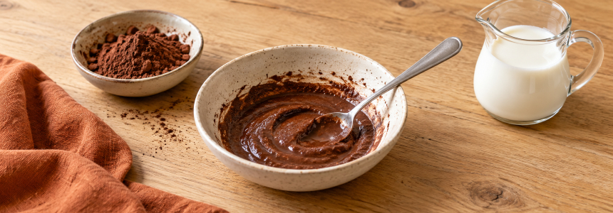 Pudră de cacao amestecată cu lapte până la obținerea unei paste fine, într-un bol de ceramică
